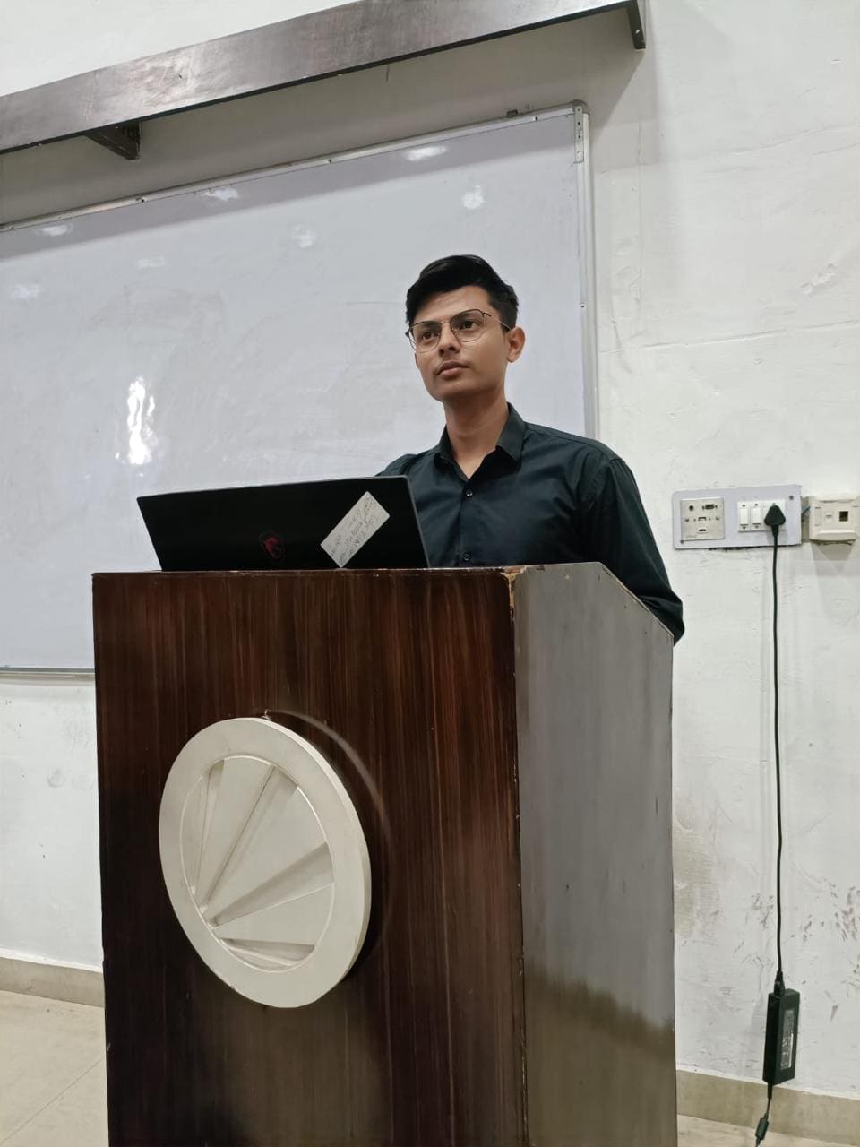 Suman Sourabh presenting from a lectern to a lecture hall
