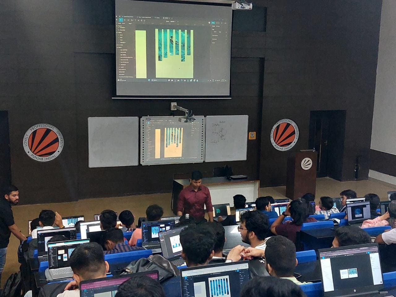 Design work projected on screen while students follow along at their machines